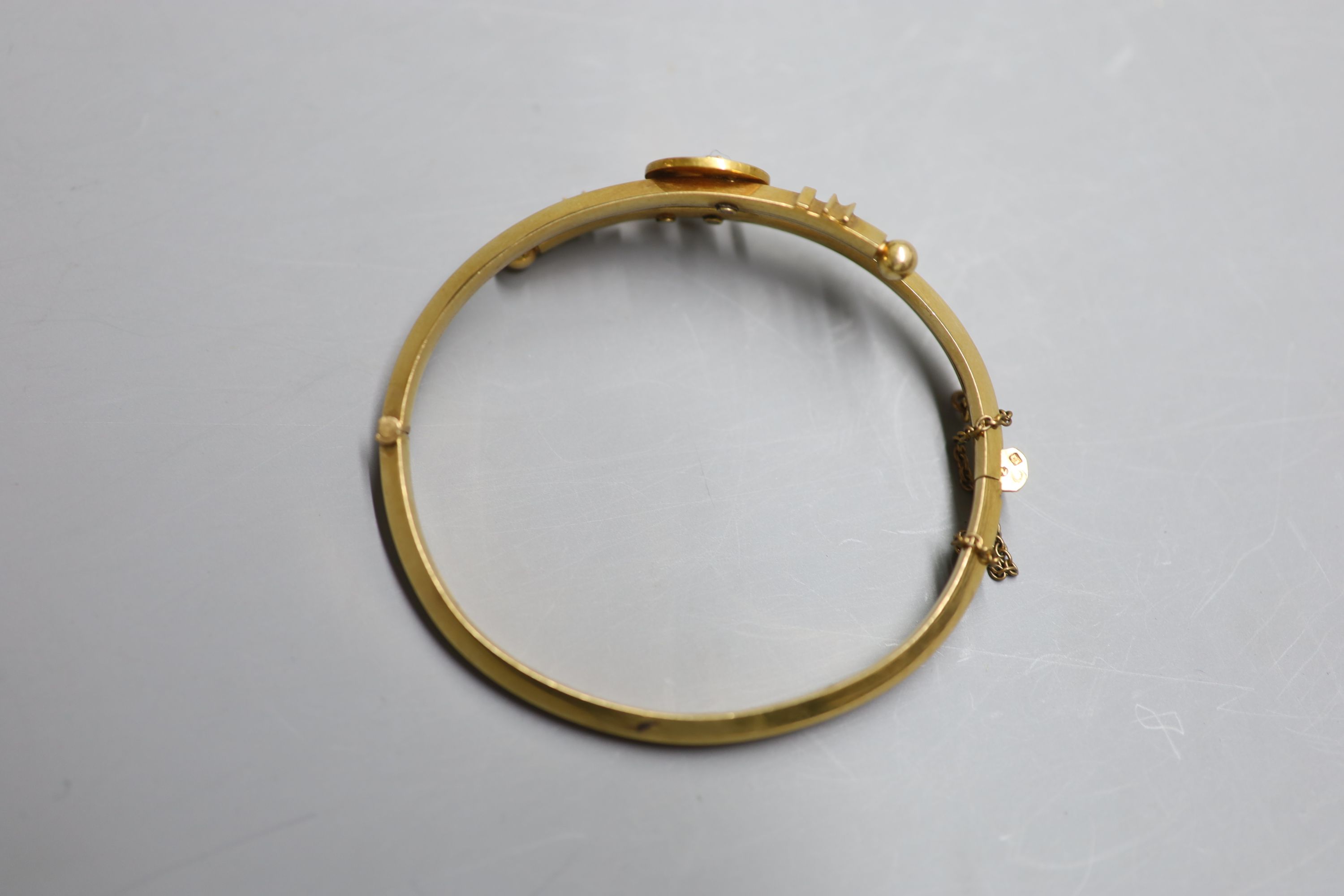 A late 19th century continental yellow metal and seed pearl set crescent moon and star crossover hinged bangle, gross 13.6 grams.